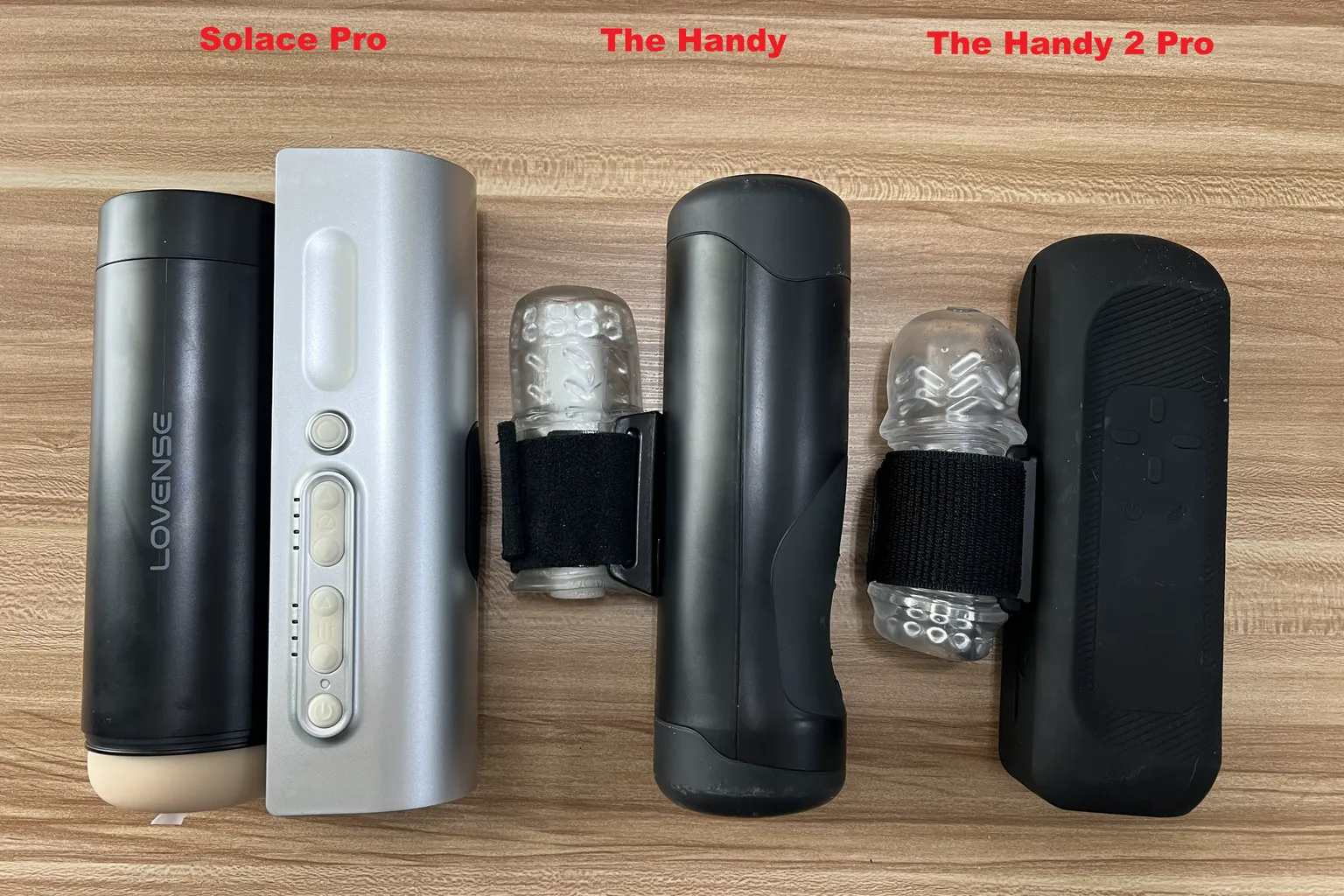Lovense Solace Pro, der ursprüngliche The Handy und The Handy 2 Pro im direkten Größenvergleich mit unterschiedlichen Gehäuseformen und Befestigungen für die Masturbator-Hülsen