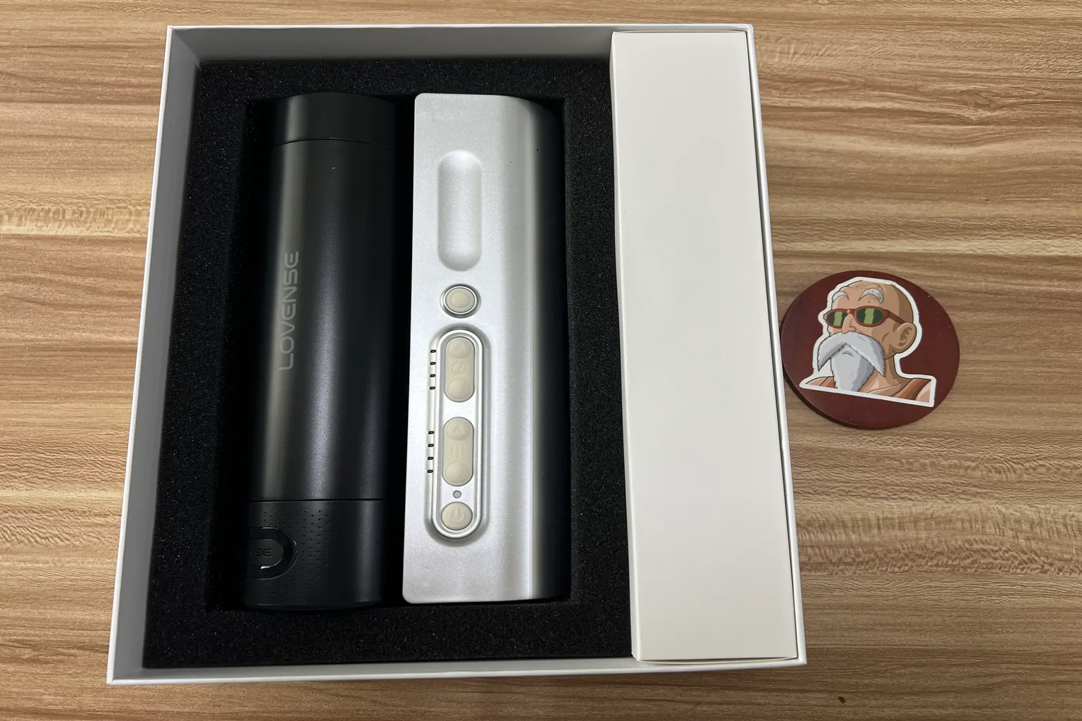 Lovense Solace Pro beim Auspacken: Das Gerät liegt geschützt in schwarzem Schaumstoff, rechts befindet sich die Zubehörbox