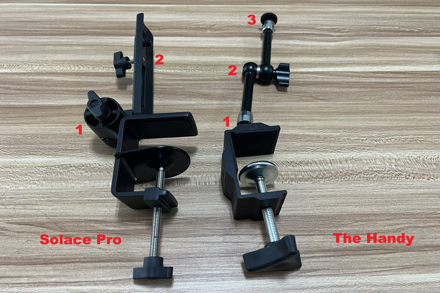 Vergleich der mitgelieferten Tischhalterung des Lovense Solace Pro mit der verstellbaren Armhalterung von The Handy, einschließlich markierter Verstellpunkte