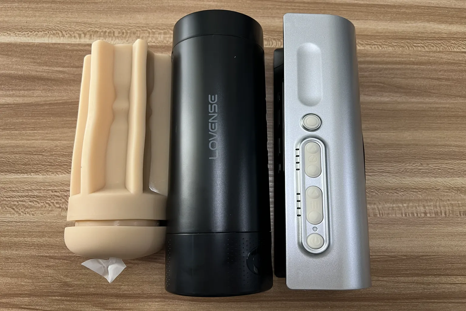Zerlegter Lovense Solace Pro mit herausnehmbarer TPE-Hülse links, schwarzem Gehäuse in der Mitte und silbernem Hauptgerät rechts