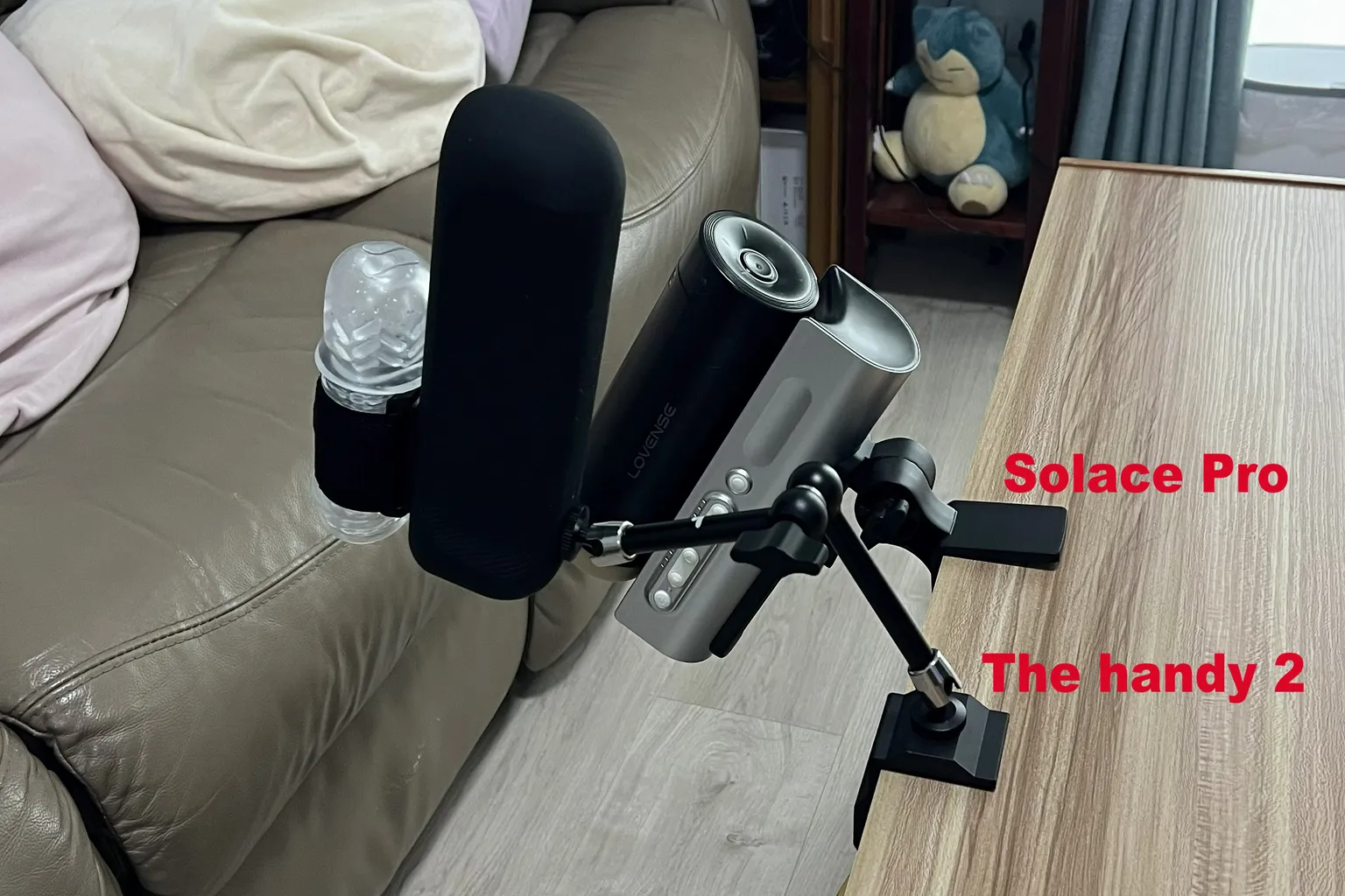 Lovense Solace Pro und The Handy 2 mit ihren jeweiligen Halterungen an einer Tischkante befestigt, um Montageposition und Einstellwinkel zu vergleichen